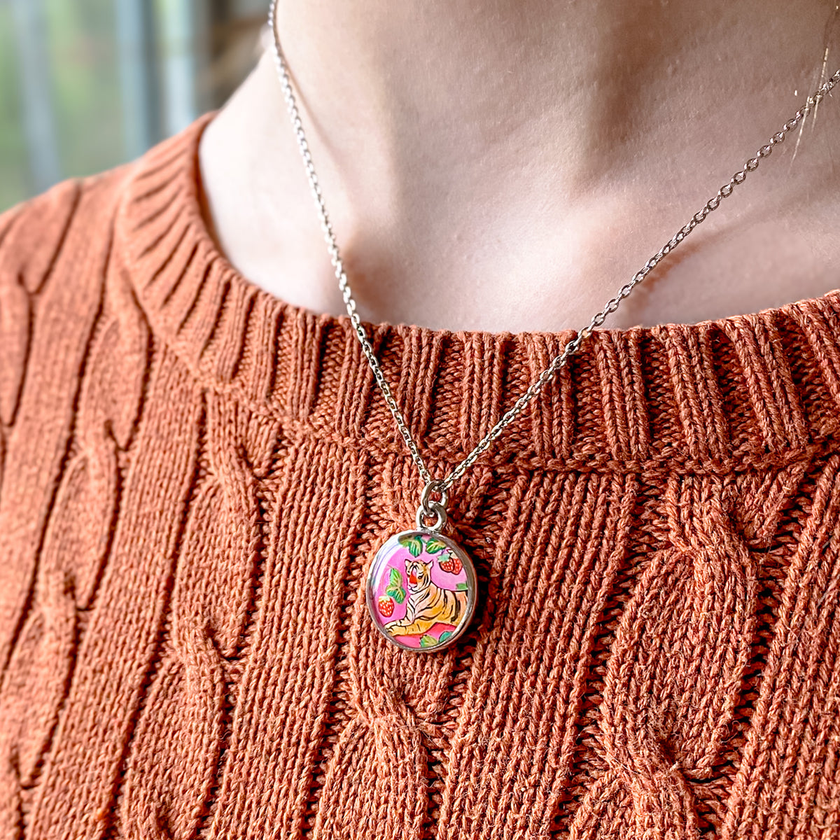 a close up of a person wearing a sweater and a necklace