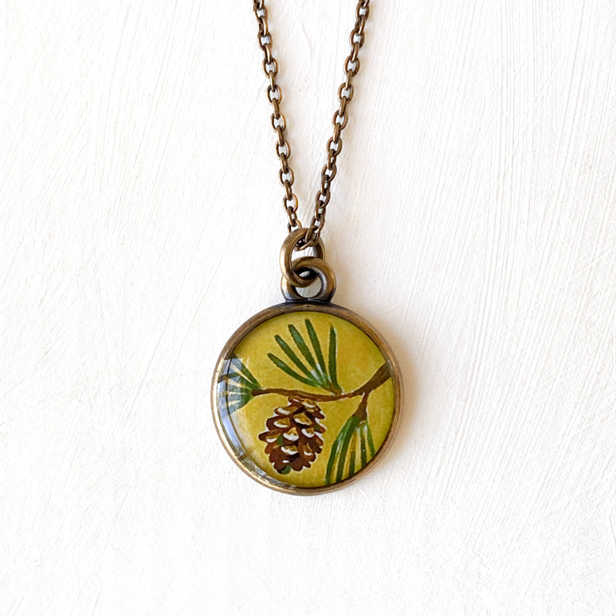 a necklace with a picture of a pine cone on it