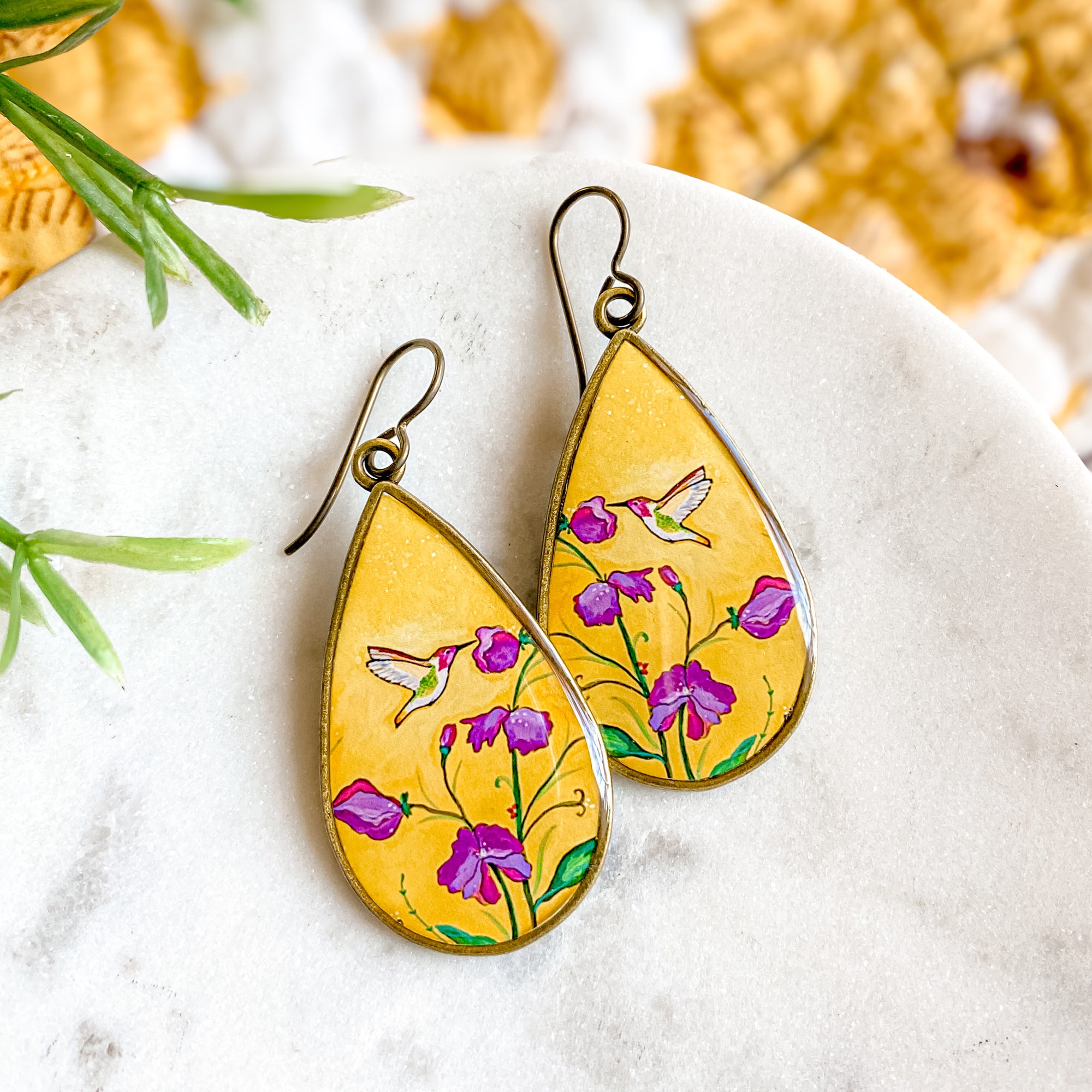 a pair of yellow earrings with purple flowers painted on them