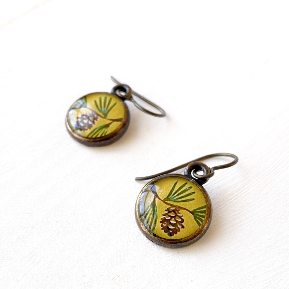a pair of earrings with pine cones on them