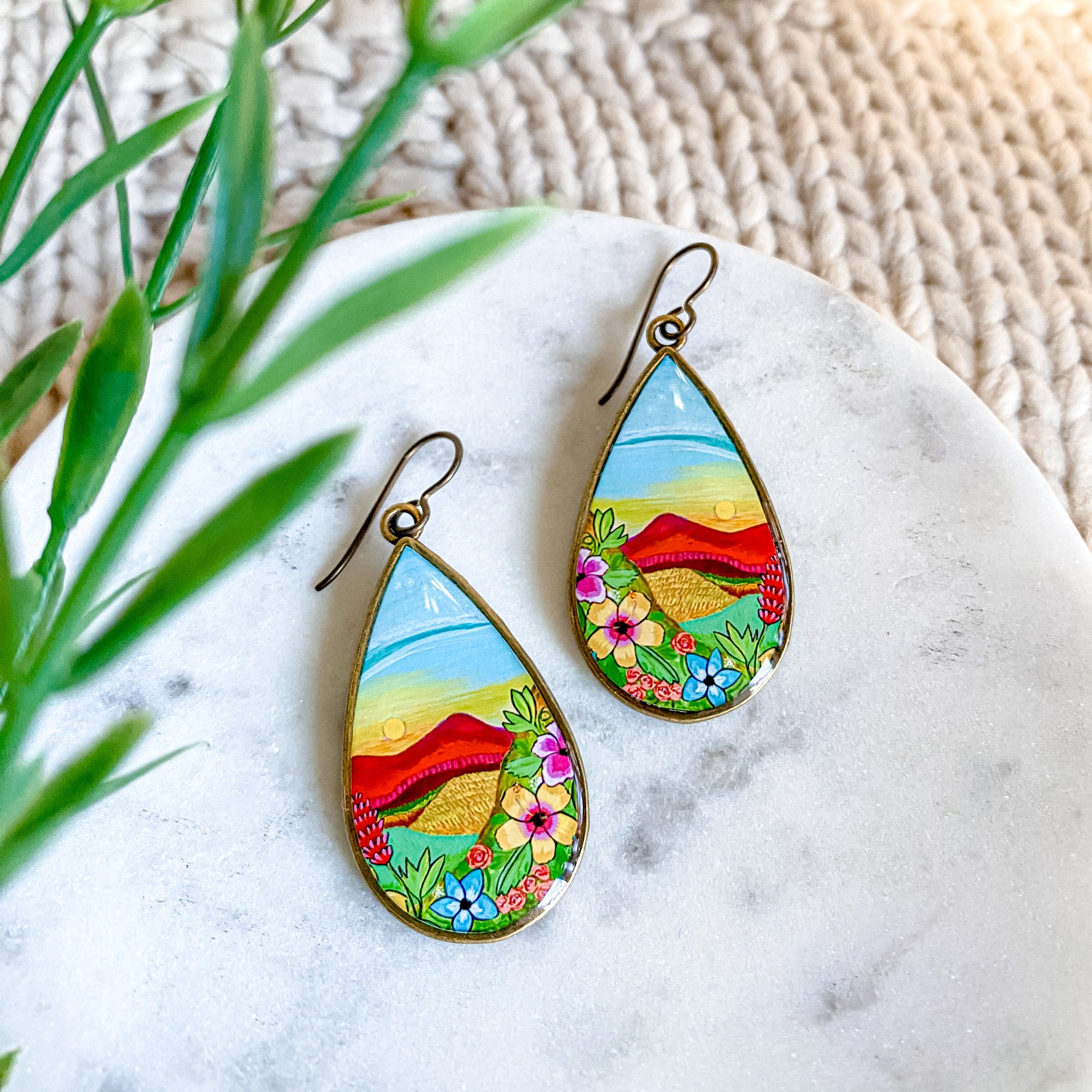 a pair of earrings with a painting on them