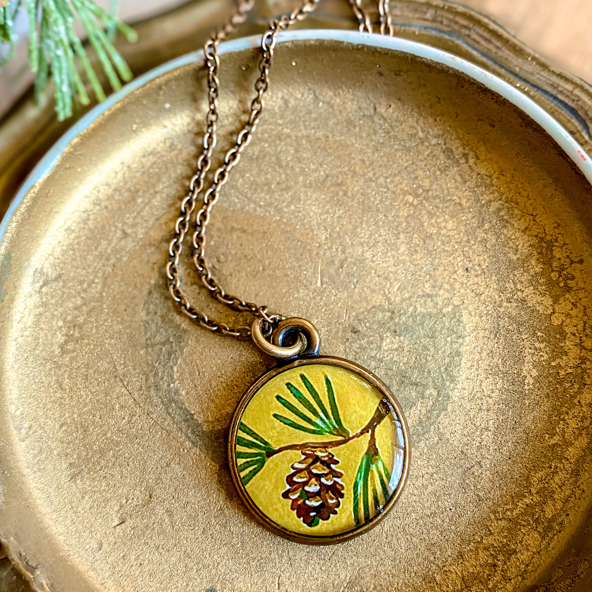 a necklace with a picture of a pine on it