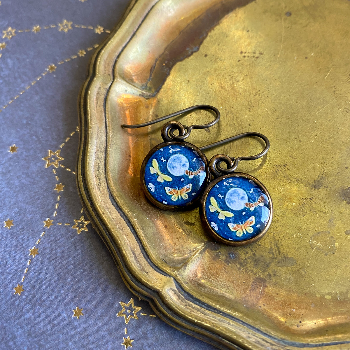 a pair of blue earrings sitting on top of a metal tray
