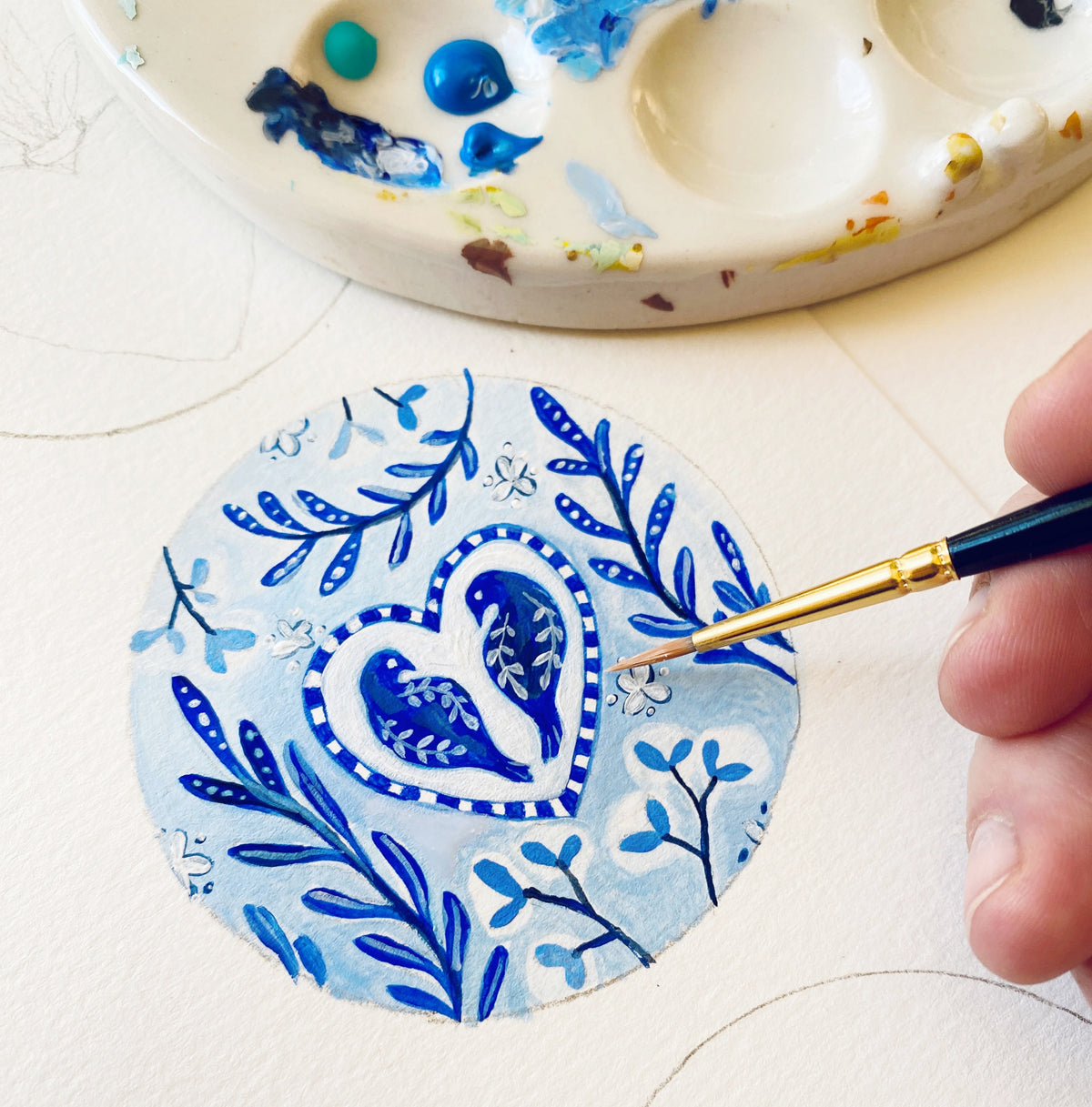 a person is painting a blue and white plate