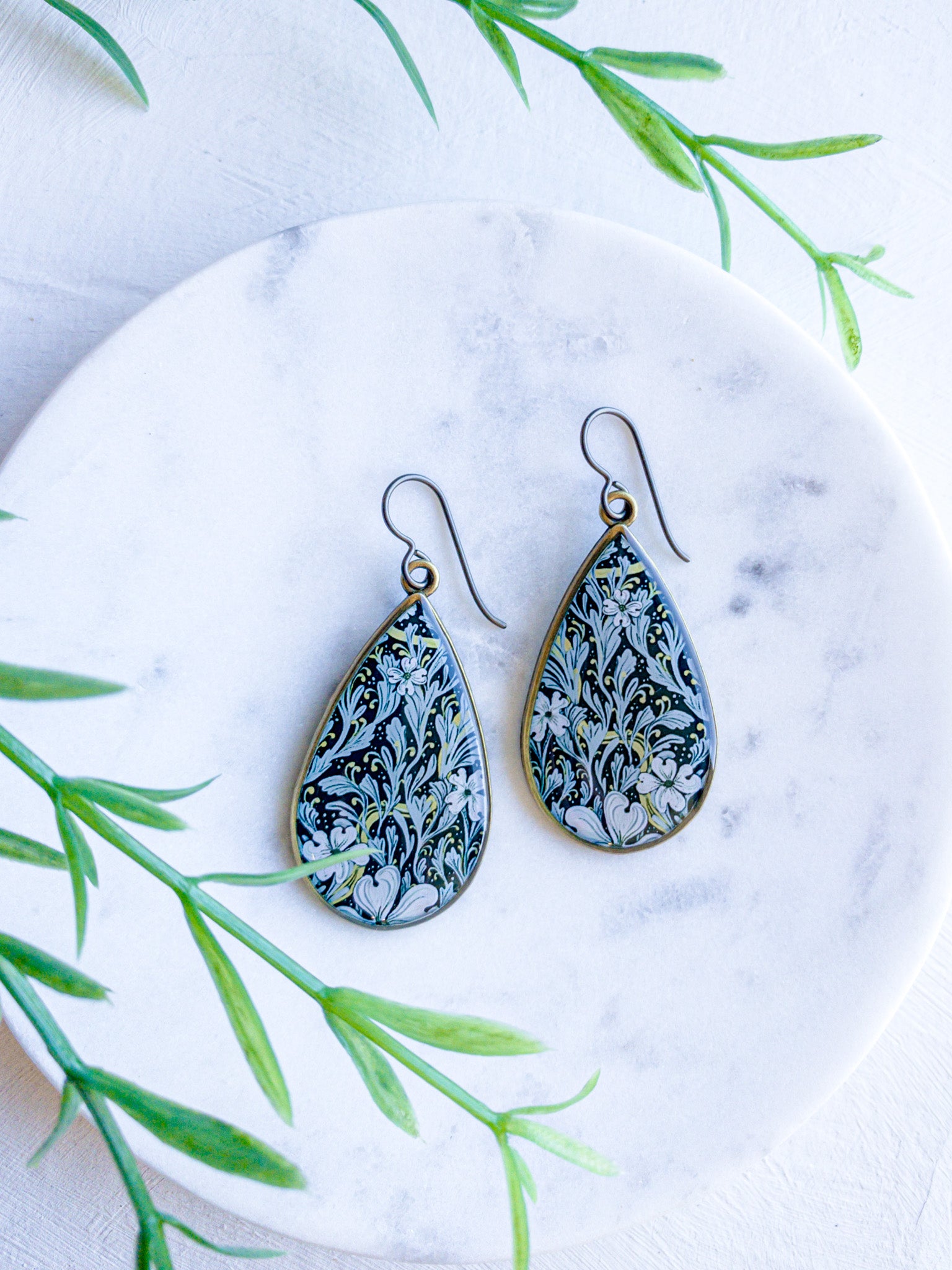 a pair of blue and white earrings sitting on top of a plate