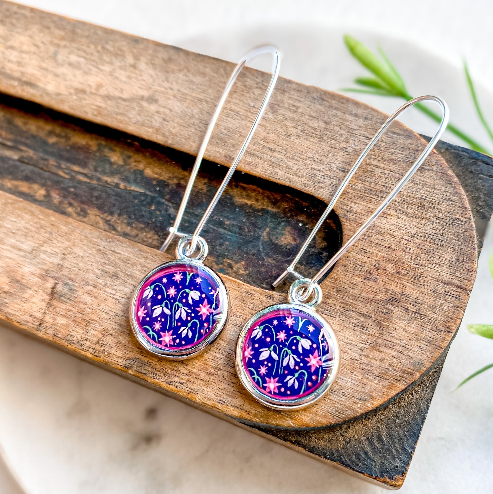 a pair of earrings sitting on top of a wooden board