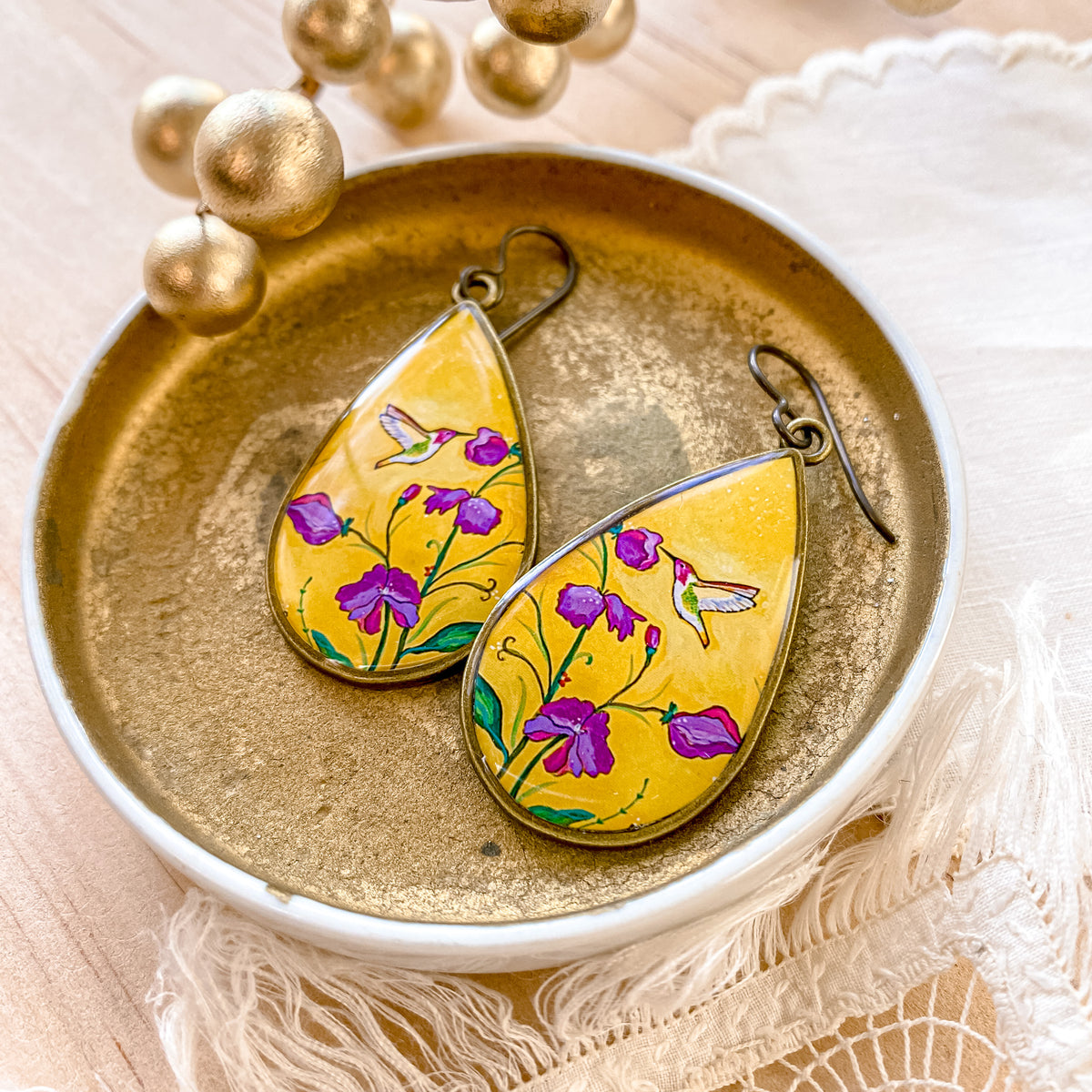 a pair of yellow earrings with flowers painted on them