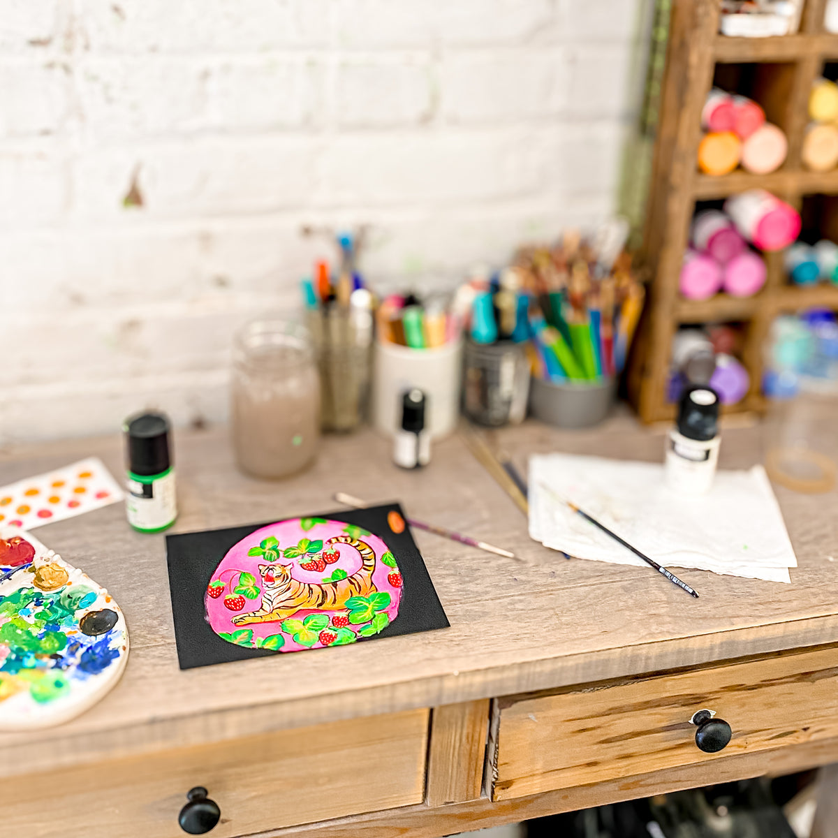 a wooden desk with a painting and art supplies on it