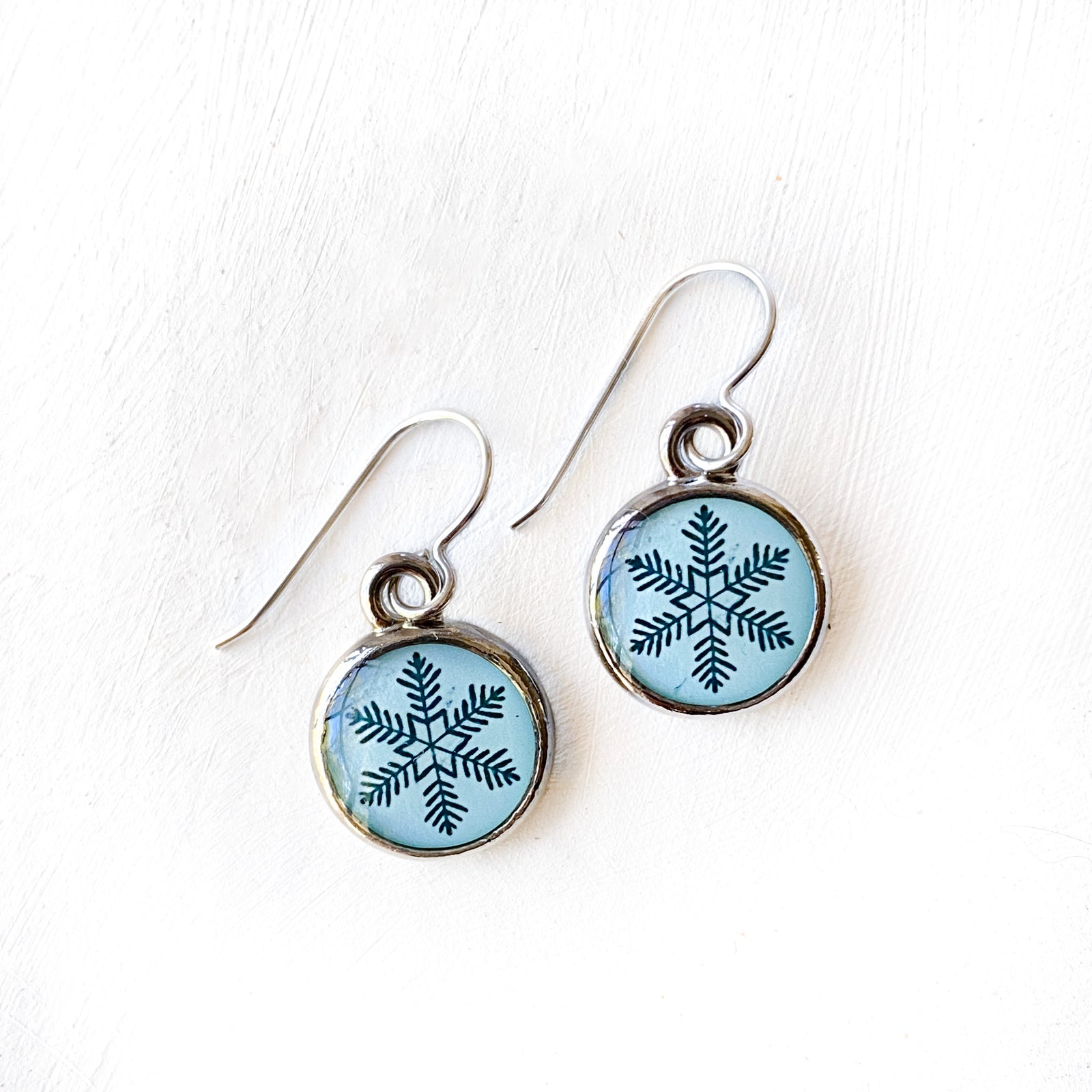 a pair of earrings with a snowflake design