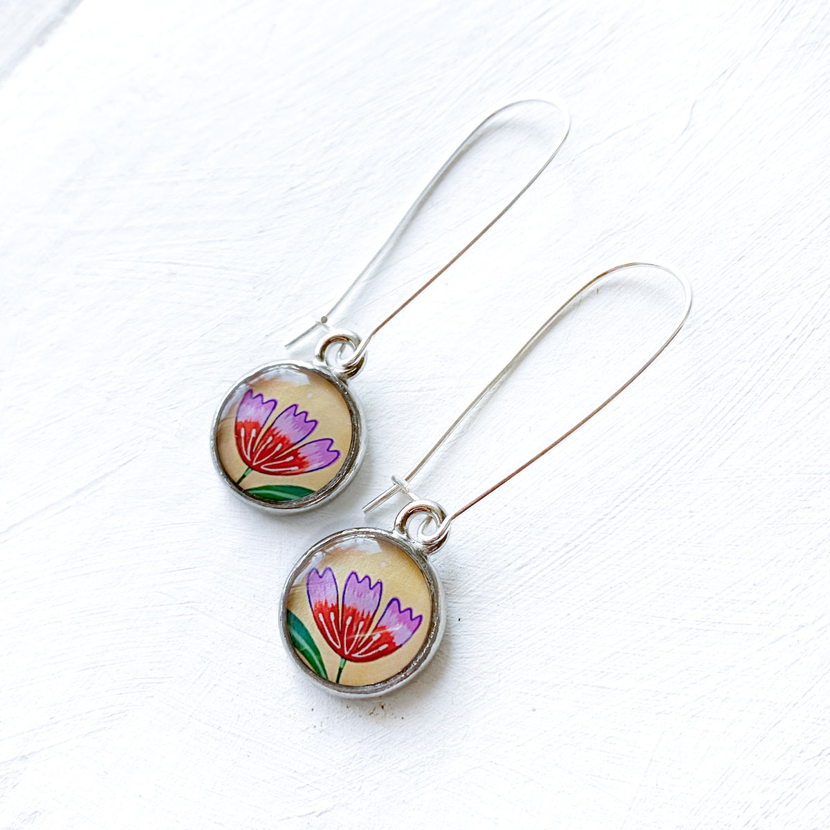 a pair of earrings with flowers painted on them