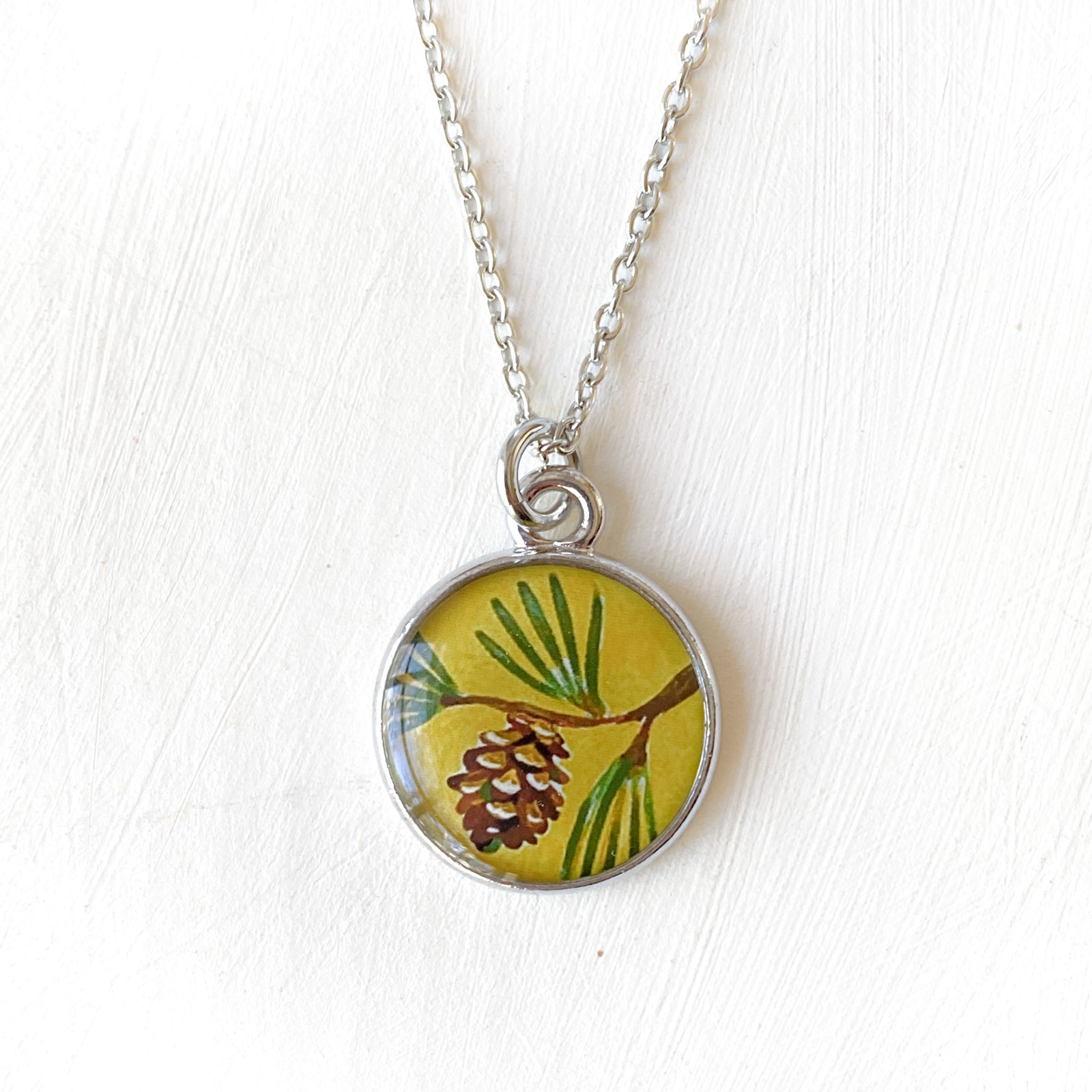 a necklace with a picture of a pine cone on it