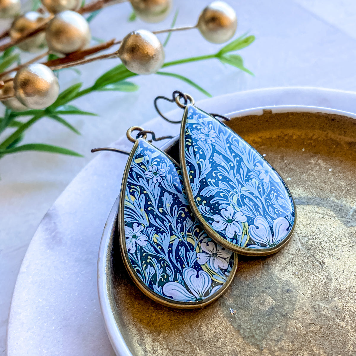 a pair of blue and white earrings sitting on top of a plate